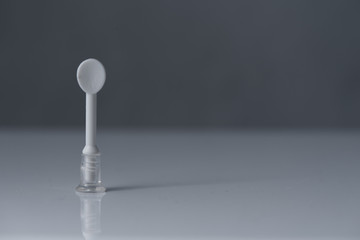 Puller-sucker or Suction cup for contact lenses, stands on a white table and gray background