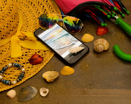 vacation photo.  pictured hat glasses umbrella in the sand shells phone