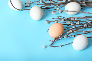 Raw white chicken eggs with willow on a blue background, top view with place for text.