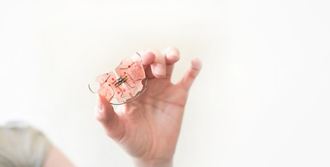 A dental plate in hand that helps align growing teeth against an white background. An orthodontic trainer. A way to have a beautiful smile and healthy teeth.