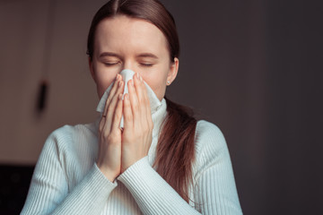 Cough in tissue covering nose and mouth when coughing. European woman sick with flu at home. - obrazy, fototapety, plakaty