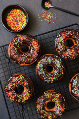 American donut with chocolate and candy on a concrete background.
