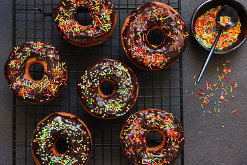 American donut with chocolate and candy on a concrete background.