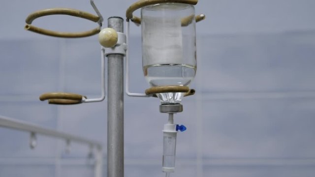 Close-up of saline solution in clinic. Close-up saline solution drip for patient in hospital. Close-up iv fluid intravenous drip saline for patient sleep on the bed, in the hospital.