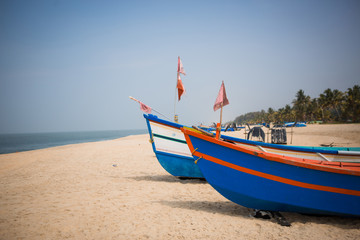 Naklejka na ściany i meble Fishing boat of Indian fishermen on the sandy beach in Kerala, fishing village Mararikulam. Bright colorful boat among palm trees