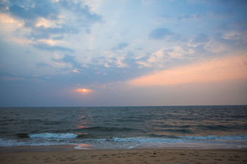 Orange sunset in the sea in India - orange and pink sky, dark blue sea. The outline of a ship on the horizon at sea