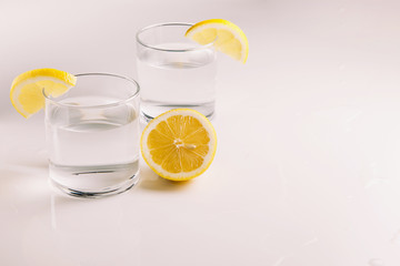 Lemon water in a glass with a slice of lemon on a light background with a place for text side view