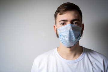 A bearded man in a medical mask looks at the camera. Self isolation
