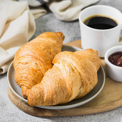 Croissants on a plate with coffee and strawberry jam. pastries for Breakfast
