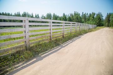 Fototapeta na wymiar white wooden fence of a farm on a sunny day