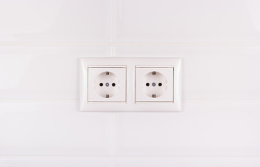 Double socket on white tile background. European electrical outlet