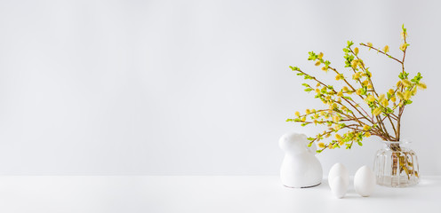 Home interior with easter decor. Willow branches in a glass vase, easter eggs on a light background