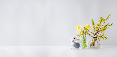 Home interior with easter decor. Willow branches in a glass vase, easter eggs on a light background