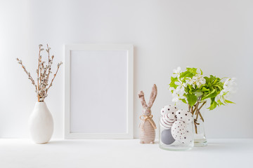Home interior with easter decor. Mockup with a white frame and spring flowers in a vases on a light...