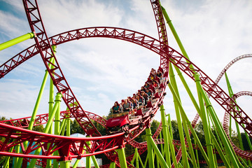 Rollercoaster large loops in an amusement park. The cabin with cheerful people laughs furiously and...