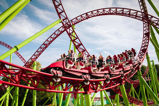 Rollercoaster large loops in an amusement park. The cabin with cheerful people laughs furiously and screams while riding an amusement ride. Summer panorama.