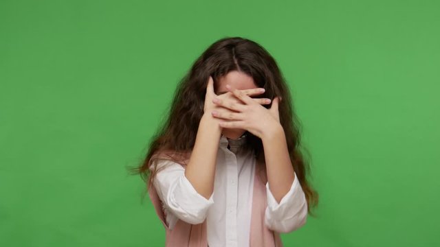 Don't want to look! Upset teenage brunette girl in white shirt closing eyes not to see something unpleasant shameful, gesturing stop, avoiding problems. indoor studio shot isolated on green background