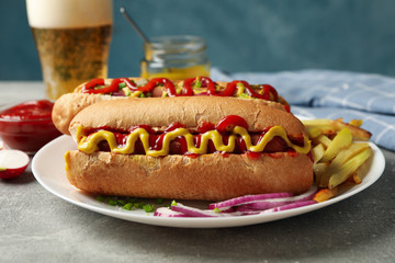 Tasty hot dogs, beer and fries potato on gray table