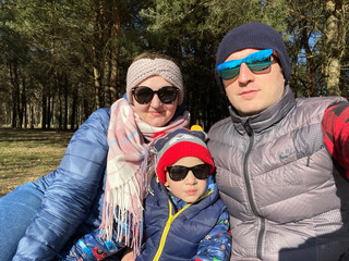 Family consist of mother, father and son all in sunglasses take selfie in city park