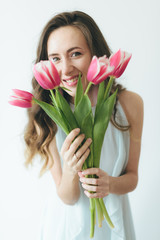 Beautiful girl hiding behind a bouquet of pink tulips, girl and tulips