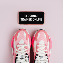 New sneakers and smartphone on a pink background. App for training indoors. Online Fitness program. Home online workout. Top view, flat lay