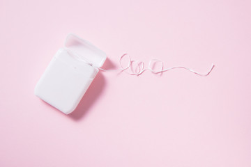Dental floss in white plastic box on pink background