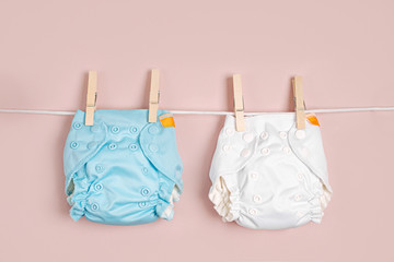 Reusable cloth baby diapers drying on a clothes  line. Eco friendly cloth nappies on a pink...