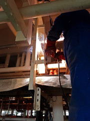 Welder welding steel angle bars for piping onboard a ship
