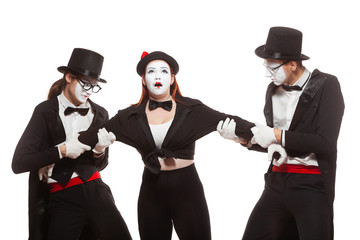 Portrait of three mime artists performing, isolated on white background. Two men pull the girl to...