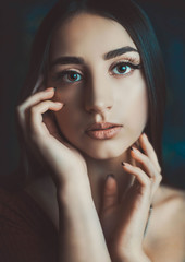 Fototapeta na wymiar Closeup beauty portrait of a beautiful young girl of twenty years old. With natural makeup. Holds hands in the face. Beauty and health of young girls. Natural aesthetic beauty of a woman.