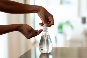 Black African American woman hand using antibacterial antiseptic hand sanitizer gel