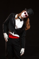 Portrait of male mime artist performing, isolated on black background. Man is standing straight tilt his head with his hand on the stomach