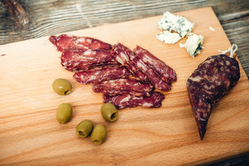 smoked meat and sausage with olives on the kitchen board