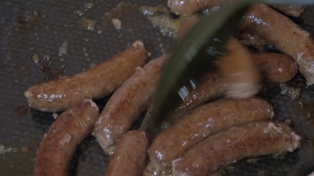 Slow motion of Grill Tongs flipping Sausages on a sizzling hot grill plate