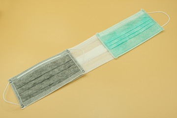 three kind of charcoal green and white paper mask surgical filter dust pollution and disease corona virus. safety medical equipment. Isolated on yellow background.