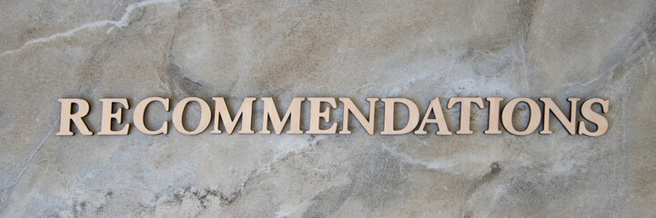 recommendations , writen wooden letters on stone background