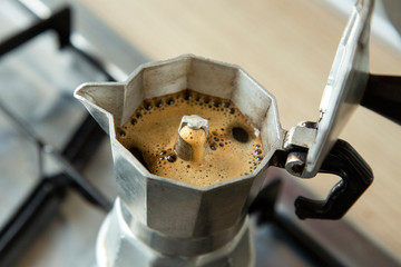 Moka con caffè in uscita sopra i fornelli