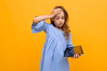 pensive girl with a tablet in hands on a yellow background with copy space
