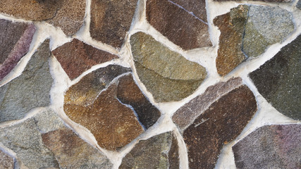 stone wall texture of bright smooth natural stones of different colors. masonry construction