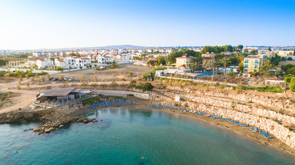 Fototapeta premium Aerial bird's eye view of Kapparis (fireman's) beach in Protaras, Paralimni, Famagusta, Cyprus. Tourist attraction golden sand Kaparis bay with boats, sunbeds, sea restaurants, water sports from above