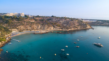 Fototapeta premium Aerial bird's eye view of Konnos beach, Cavo Greco Protaras, Paralimni, Famagusta, Cyprus. Famous tourist attraction golden sandy bay with boats, yachts in the sea, sunbeds, water sports, from above.