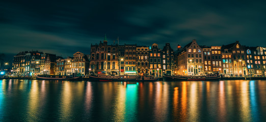 Fototapeta na wymiar Amsterdam City panorama, illuminated buildings or dancing houses with reflection in water canal at night, Netherlands.