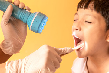 Close up doctor examining throat of patient with tongue depressor.