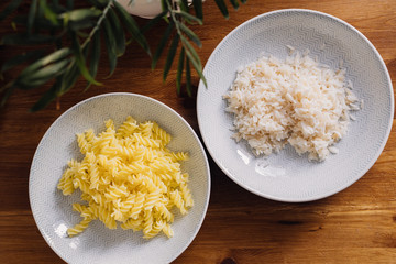rice and pasta in plates standing on a wooden table