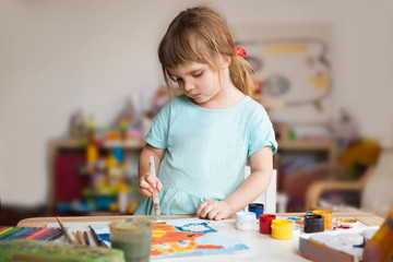 Little girl draws paints at home. The concept of distance learning online school. 