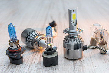 Set of different auto lamp for repair headlight on white wooden background. Modern electric bulbs