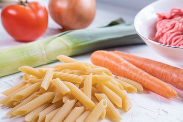 Macaroni, carrot, leak, onion, tomato and minced meat for pasta bolognesa. Italian cuisine. Close up view.