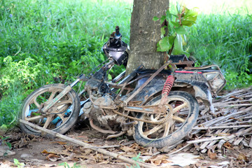 Old broken motorcycle near a tree