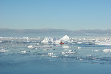 Small boat sailing past a big iceberg, Greenland