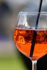 glass of fresh sparkling bubbles in orange aperol spritz drink cocktail with black drinking straw 